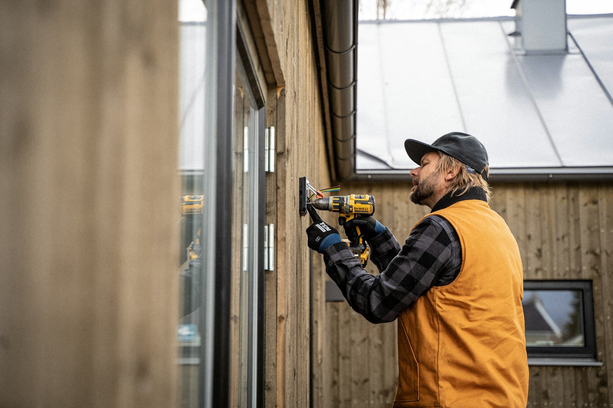 Vakman met een accuboor aan een houten gevel